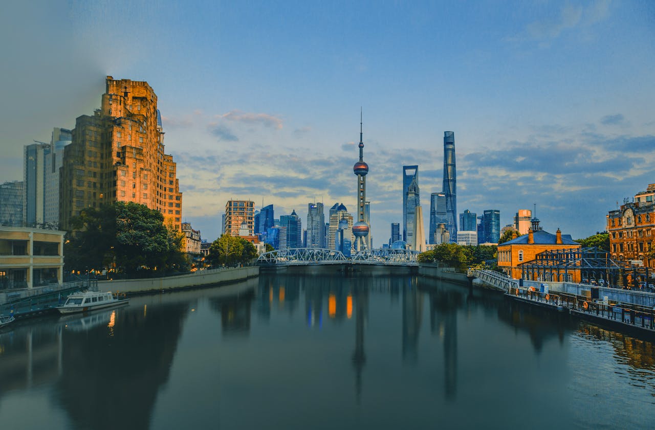 services-03 Scenic view of the Shanghai skyline at sunset with the iconic Oriental Pearl Tower reflected in the Huangpu River.